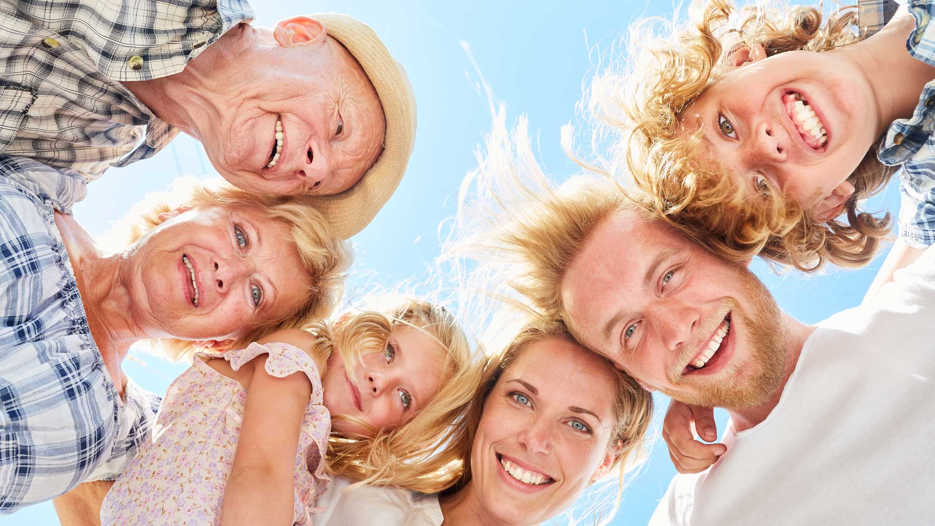 Mehrere Personen unterschiedlichen Alters stehen im Kreis und schauen von oben in die Kamera.